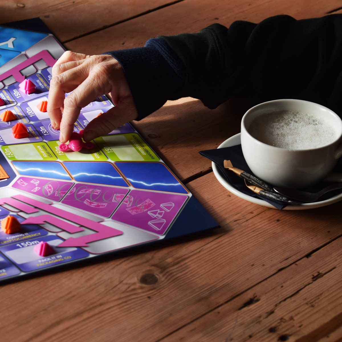 Assets Trip family board game in play, showing a player moving a colourful game piece across a vibrant strategy board. A fun and engaging 2–6 player family board game with strategic gameplay, perfect for game nights, parties and playing with friends. Part of a major board game deal and designed for replayable family entertainment.