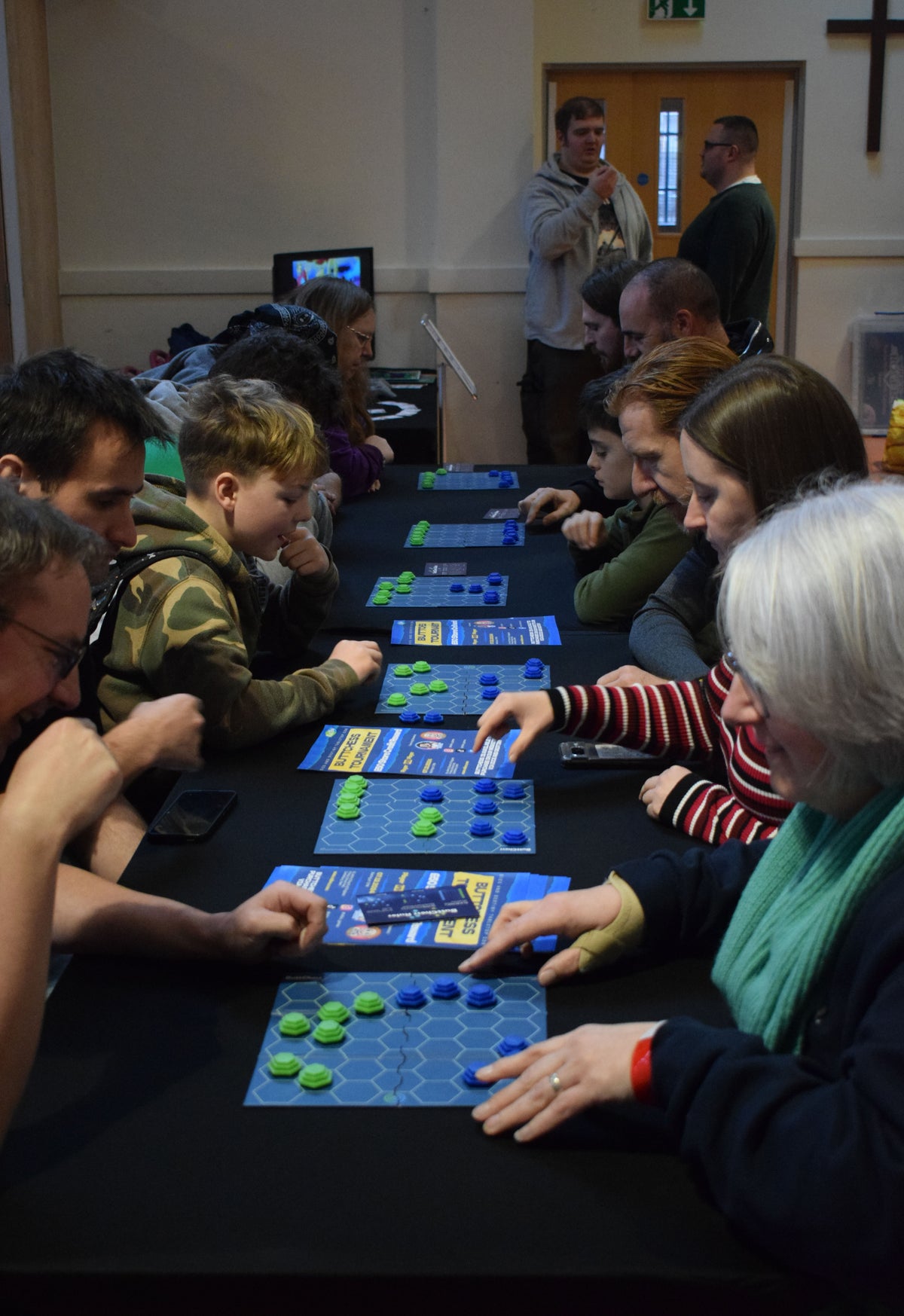 Group of players enjoying tabletop board games at an event, with ButtChess and pieces in play, showcasing social family games that are compact, portable and ideal for group game nights.