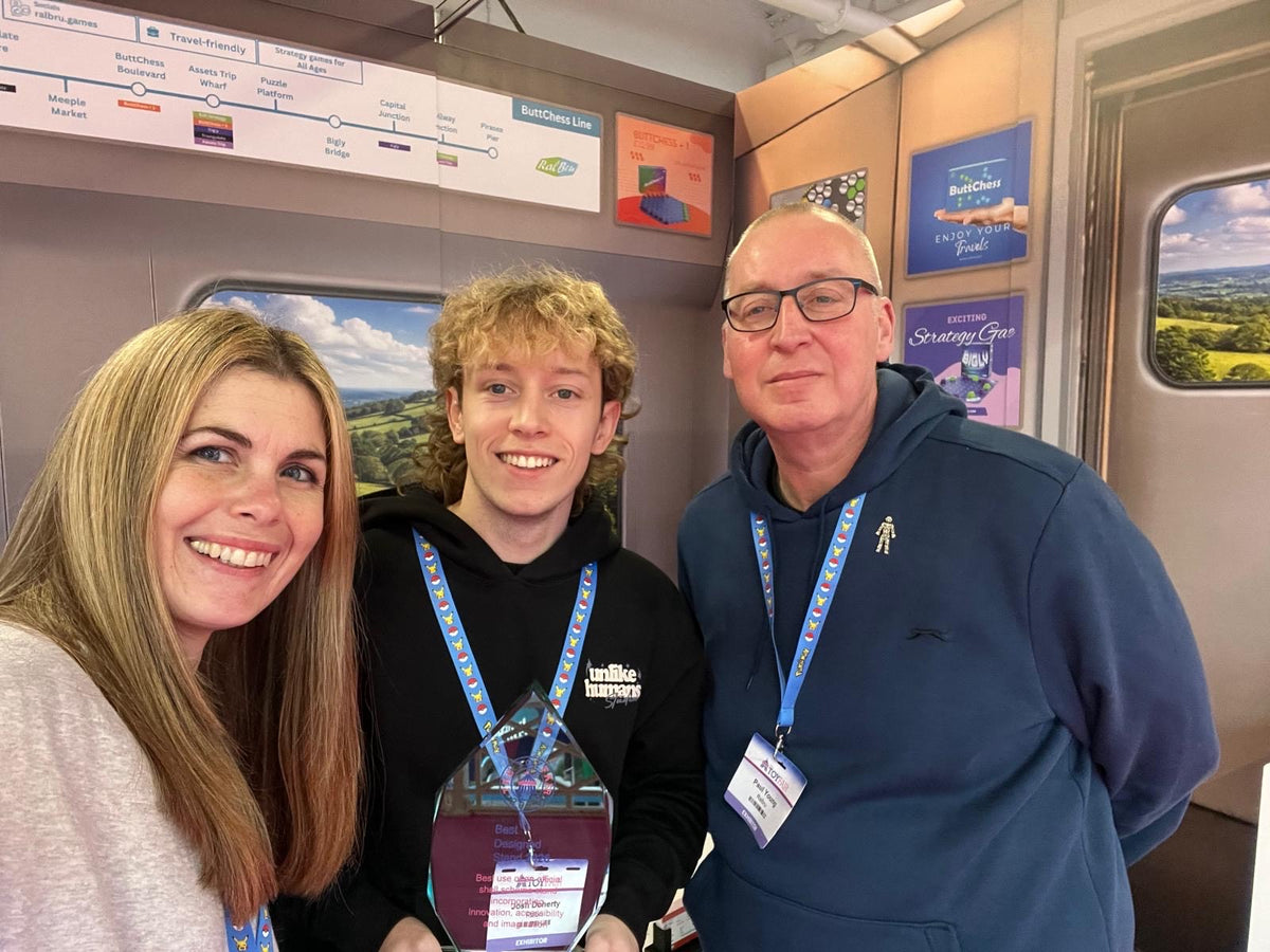 The Ralbru Team on our train them display stand holding the Best Designed Stand Trophy at the London Toy Fair 2026, showcasing our travel friendly strategy games.